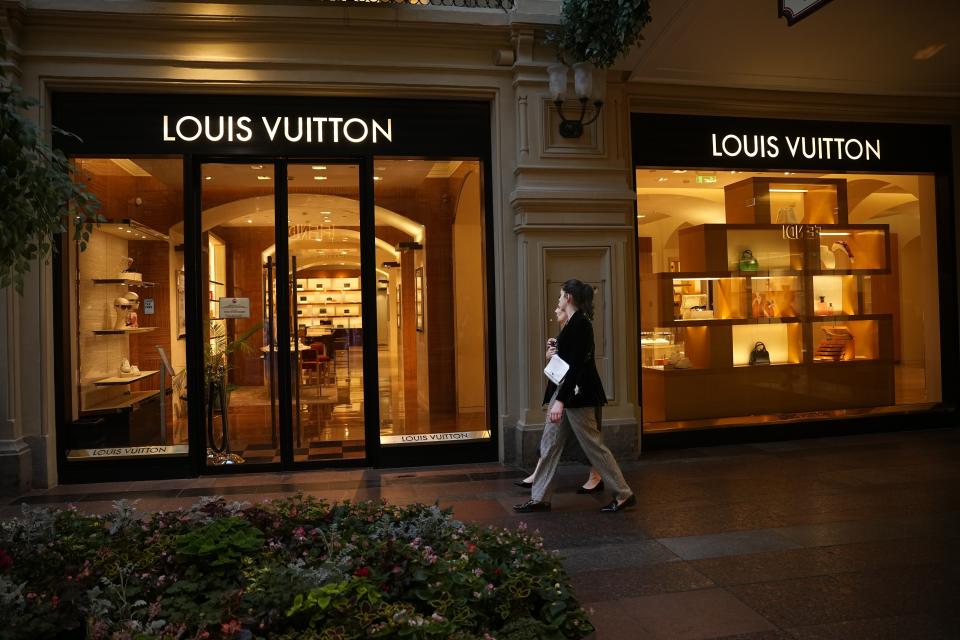 Two women walk past a Louis Voutton boutique closed due to sanctions in the GUM department store in Moscow, Russia, Tuesday, Aug. 9, 2022. Often, it's hard to tell when stores are closed. At the famous GUM department store lined with shops in Red Square, most of the closed storefronts still had the lights on and a clerk or guard inside. (AP Photo/Alexander Zemlianichenko)