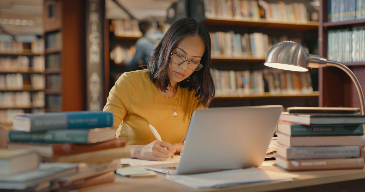 Young lady using a laptop to do research on the internet. Woman working on a project. Mixed race woman sending emails.