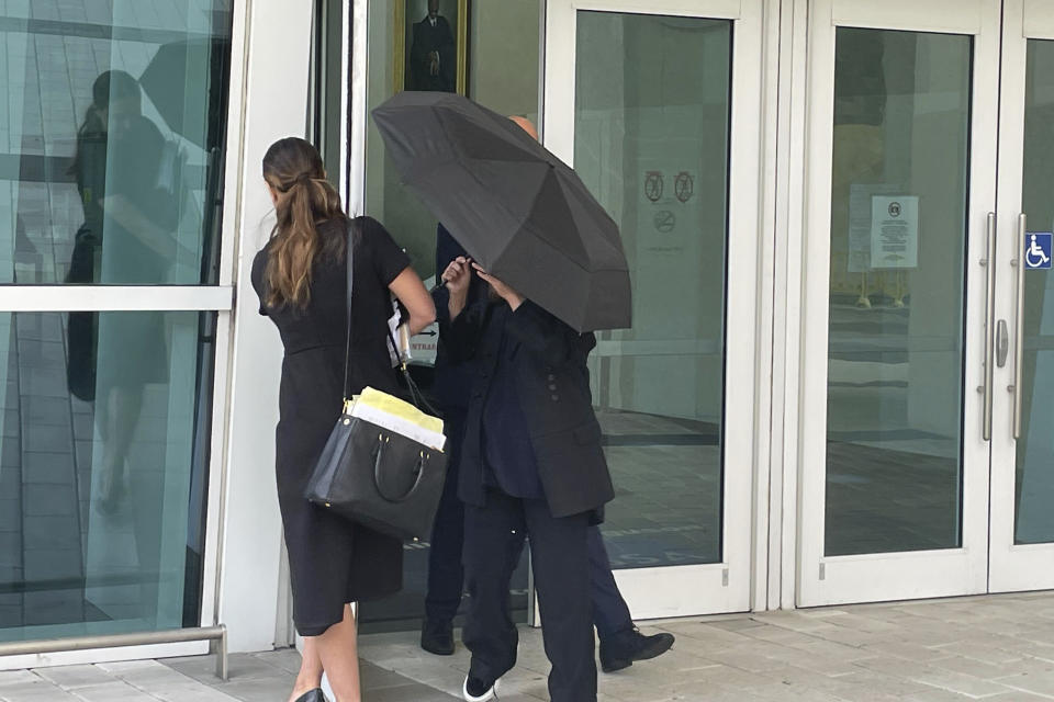 Celebrity handbag designer Nancy Gonzalez hides under an umbrella as she walks with her lawyer Andrea Lopez outside the federal courthouse Monday, April 22, 2024, in Miami. The Colombian designer, whose bags were purchased by celebrities like Britney Spears and the cast of the "Sex and the City" TV series, was sentenced to 18 months in federal prison on Monday for leading a smuggling ring that illegally imported into the U.S. crocodile handbags for sale at high end showrooms using couriers on commercial flights. (AP Photo/Josh Goodman)