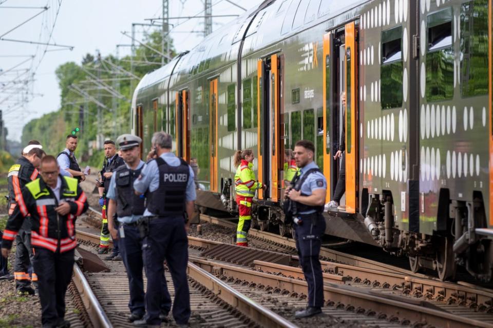 Police officers standing in front of a regional train in Herzogenrath (AP)