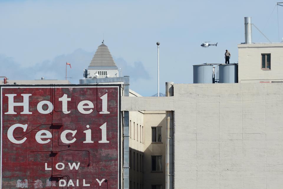 A worker stands on a water tank on the roof of the Hotel Cecil in Los Angeles California February 20, 2013. The body of 21-year-old Canadian tourist Elisa Lam was found in a water tank on the roof of the hotel three weeks after she went missing, police said. The corpse was found February 19 after hotel guests complained of low water pressure.  AFP PHOTO Robyn BECK        (Photo credit should read ROBYN BECK/AFP via Getty Images)