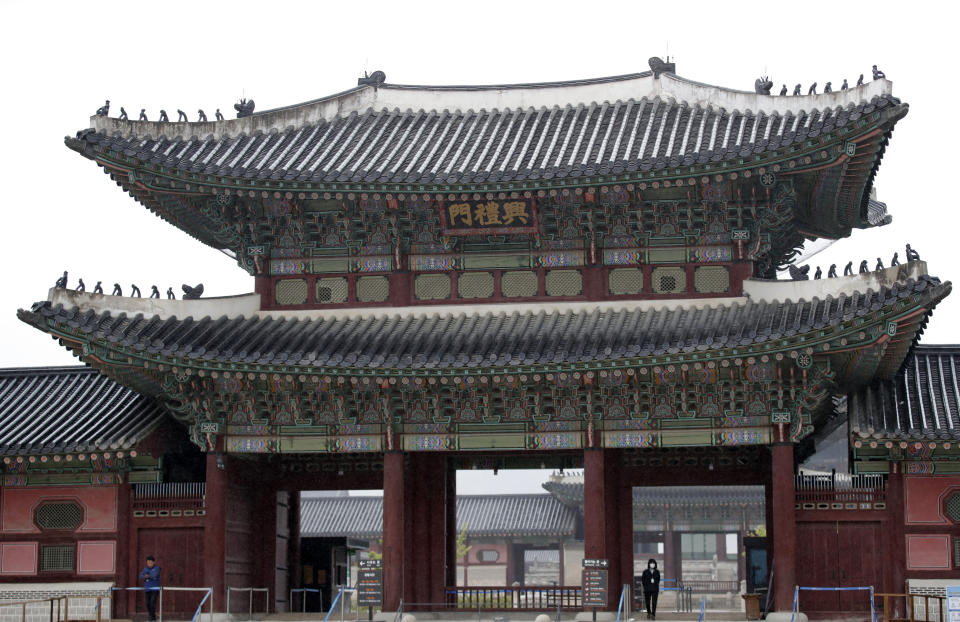 An employee, right bottom, wearing mask as a precaution against the new coronavirus, stands at the Gyeongbok Palace, the main royal palace during the Joseon Dynasty and one of South Korea's well known landmarks in Seoul, South Korea, Friday, May 15, 2020. (AP Photo/Lee Jin-man)