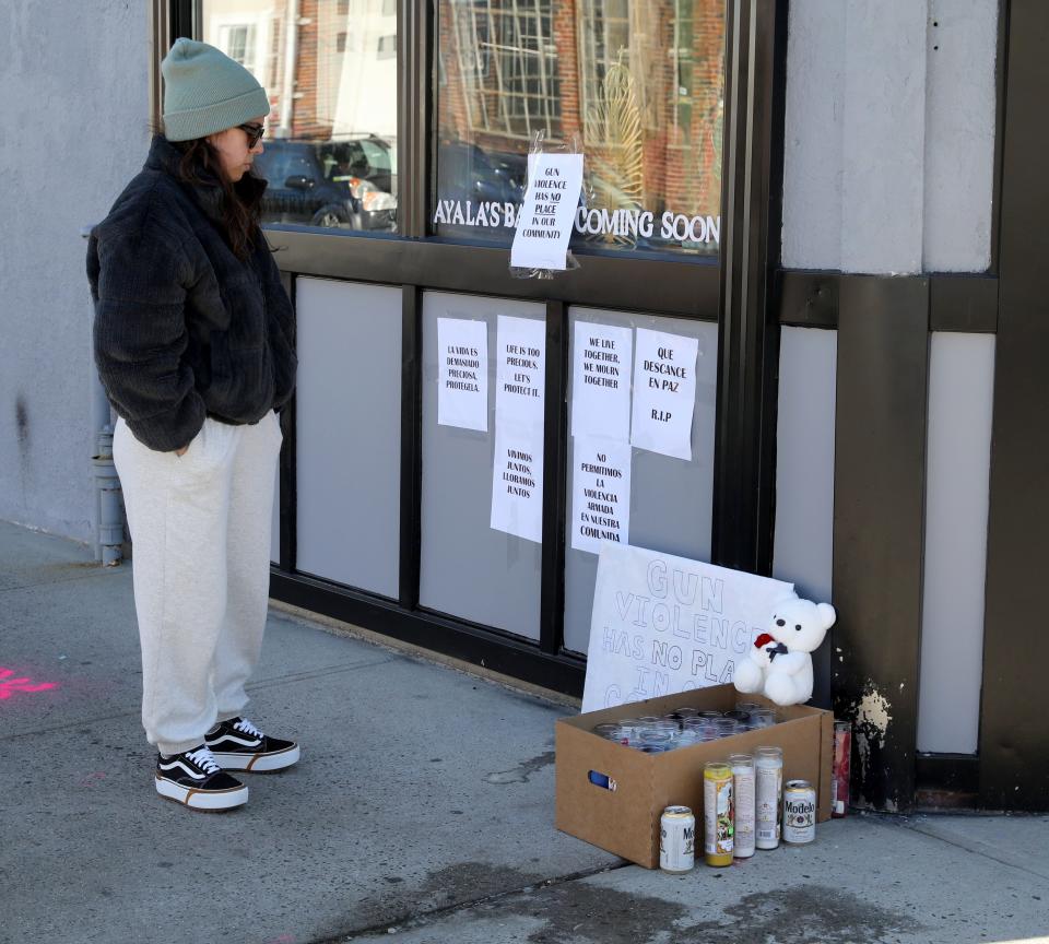 Gaby Contreras who lives in the neighborhood, looks over a memorial for a teenager that was shot by another teenager in New Rochelle, at the corner of Washington Avenue and Fourth Street in the city, Jan. 26, 2022. 