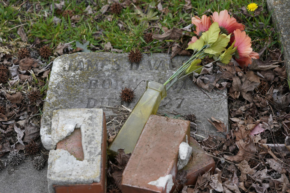 Flowers and bricks lay on a tombstones at the Lincoln Memorial Cemetery in Portsmouth, Va., Tuesday, March 23, 2021. Many Black Americans excluded from white-owned cemeteries built their own burial spaces, and their descendants are working to preserve the grounds. Racism still haunts these cemeteries, though. Many are at risk of being lost and lack the support other cemeteries have received. (AP Photo/Steve Helber)