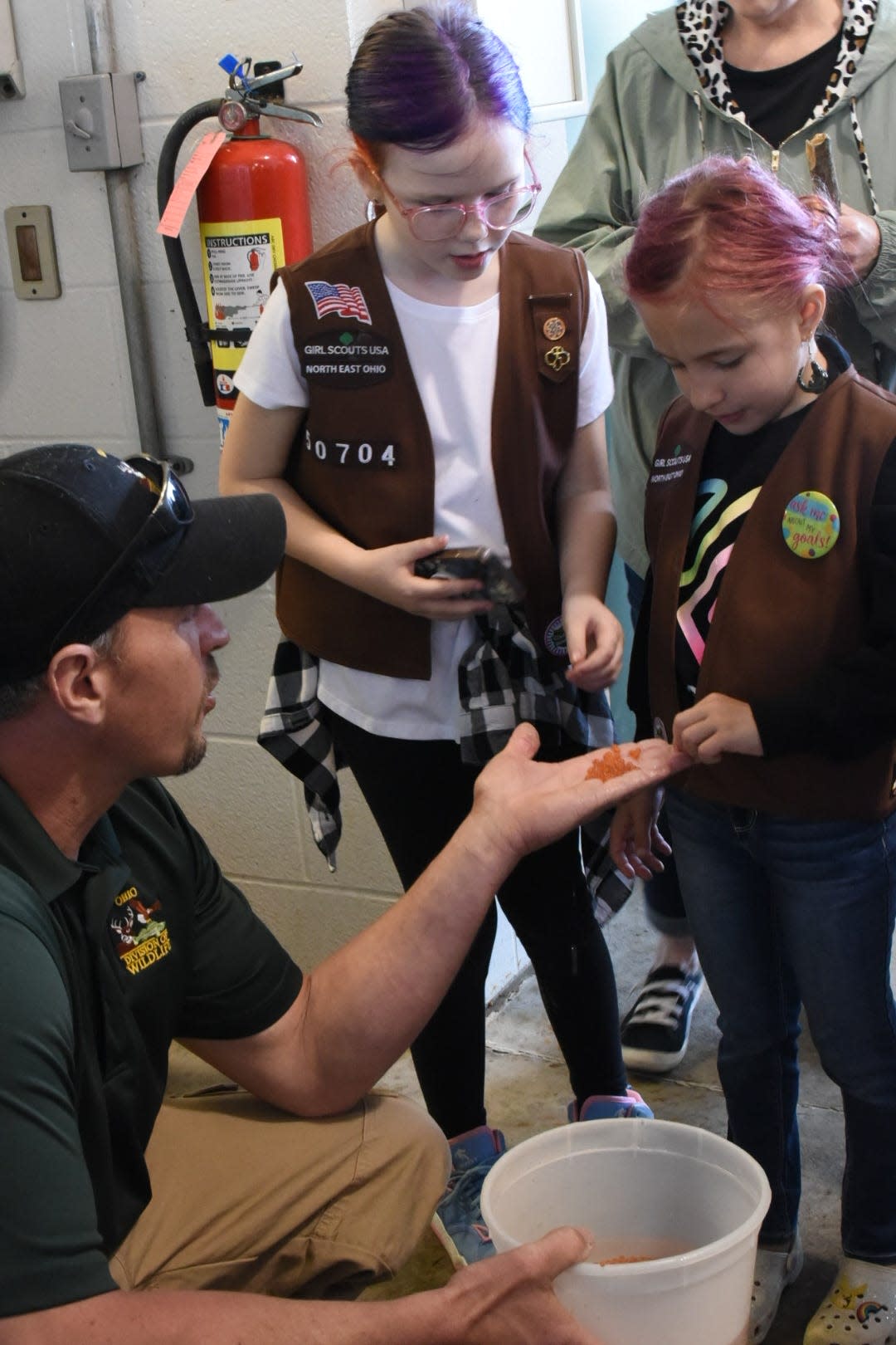 Ohio Department of Natural Resources employee Dan Kovalaske shows Kricket Brewer, 9, and Lorelei Clark, 9, some fish eggs at the Castalia State Fish Hatchery on Saturday.