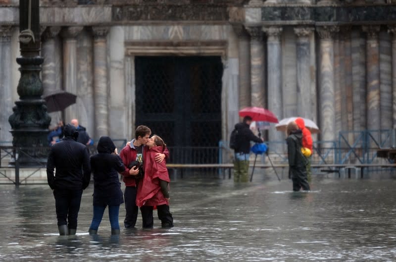 Tourists pose in St. Mark’s Square after days of severe flooding in Venice