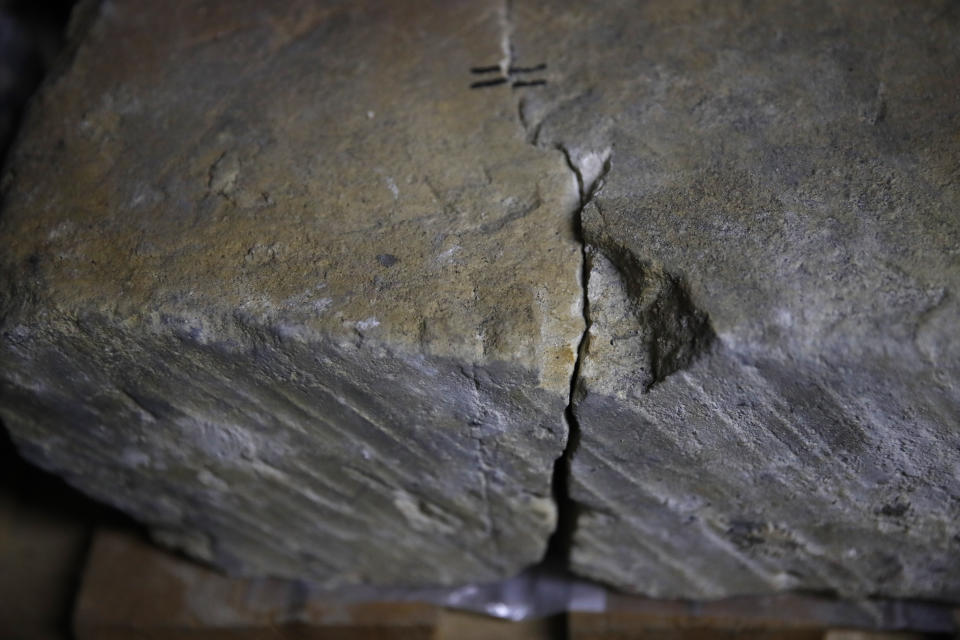 In this photo taken on Wednesday, Oct. 9, 2019, stone expert Jean-Didier Mertz displays a broken vault stone from Notre Dame cathedral in a warehouse at Champs-sur-Marne, west of Paris. Scientists at the French government's Historical Monuments Research Laboratory are using these objects as clues in an urgent and vital task, working out how to safely restore the beloved Paris cathedral and identify what perils remain inside in a race against the clock. (AP Photo/Francois Mori)