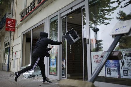 A youth throws a printer into a bank during a demonstration to protest the government's proposed labour law reforms in Nantes, France, May 26, 2016. REUTERS/Stephane Mahe