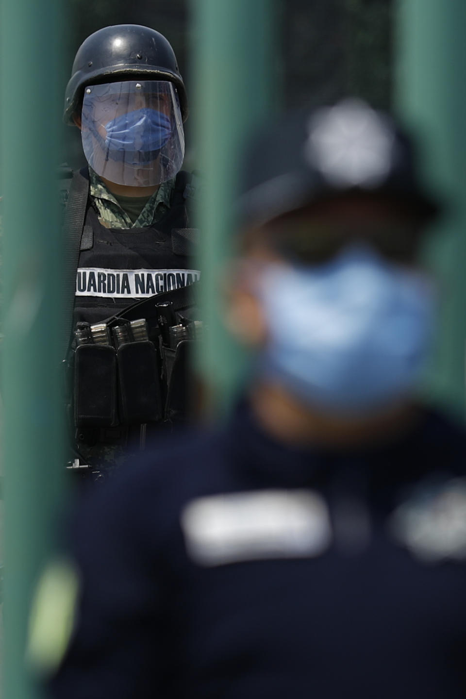 A member of the National Guard stands watch inside the gates as state police guard the street outside, at Las Americas General Hospital in Ecatepec, a suburb of Mexico City, Wednesday, May 20, 2020. Mexico City, one of the world's largest cities and the epicenter of the country's coronavirus epidemic, will begin a gradual reopening June 1, its mayor said Wednesday, even as daily new infections continued to set records. (AP Photo/Rebecca Blackwell)