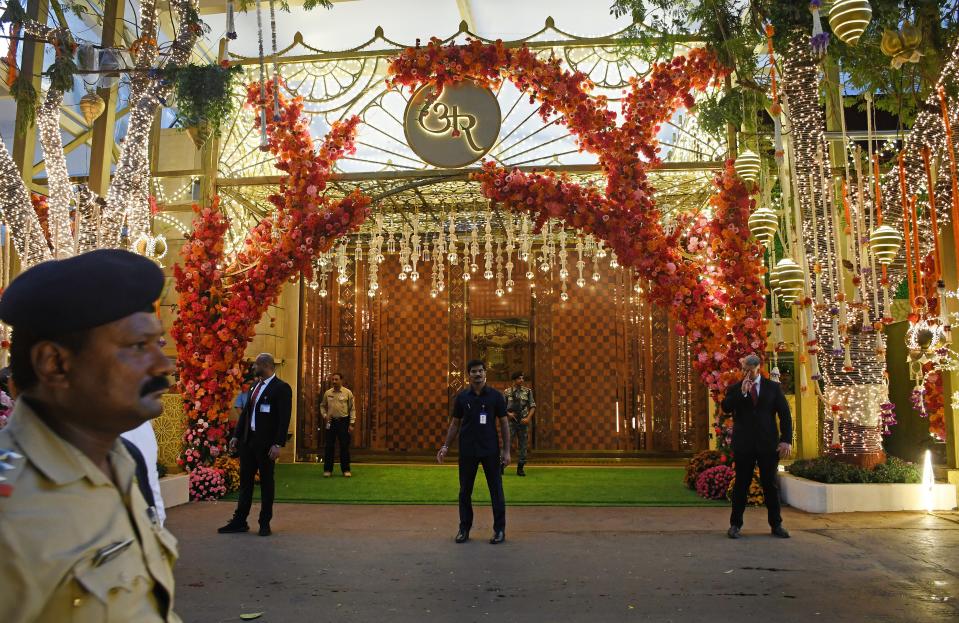 Red flowers and yellow lights decorate an archway to the Antilia tower as security guards stand outisde