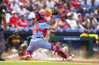 San Diego Padres' Wil Myers, left, slides in to score a run on the sacrifice fly by Ha-seong Kim as Philadelphia Phillies catcher Garrett Stubbs, right, reaches for the ball during the fourth inning of a baseball game, Thursday, May 19, 2022, in Philadelphia. (AP Photo/Chris Szagola)