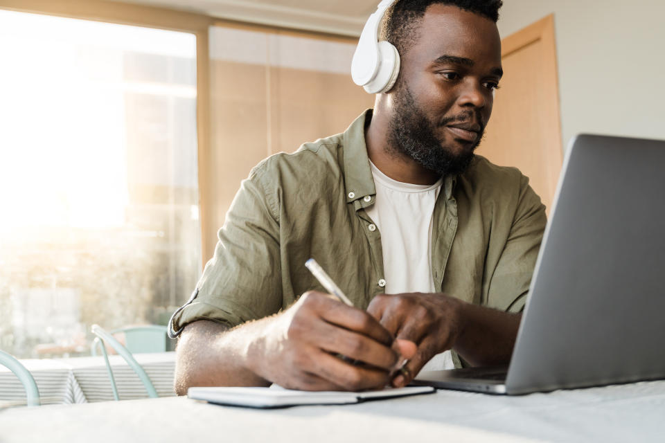 A man with headphones on working in front of a laptop