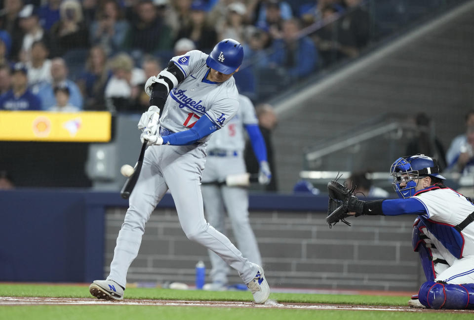 Los Angeles Dodgers designated hitter Shohei Ohtani (17) hits a solo home run next to Toronto Blue Jays catcher Danny Jansen during the first inning of a baseball game Friday, April 26, 2024, in Toronto. (Nathan Denette/The Canadian Press via AP)