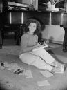 <p>The former child star takes a moment to read some mail and enjoy an apple on the floor of her Los Angeles living room, circa 1944.</p>