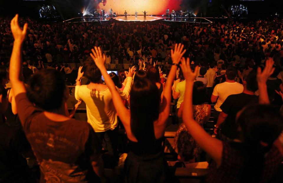 Worshippers attend a church service at the City Harvest Church in Singapore March 1, 2014. With a "prosperity gospel" that blends the spiritual and the material, City Harvest and other Pentecostal megachurches in the wealthy Asian city-state have perfected a popular and lucrative model. Now they are working to export it to the world and turn Singapore into a hub for evangelical Christianity. To match Feature SINGAPORE-MEGACHURCHES/ REUTERS/Edgar Su (SINGAPORE - Tags: RELIGION)