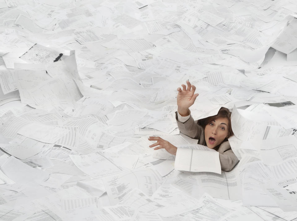 Businesswoman drowning in paperwork. (Getty)