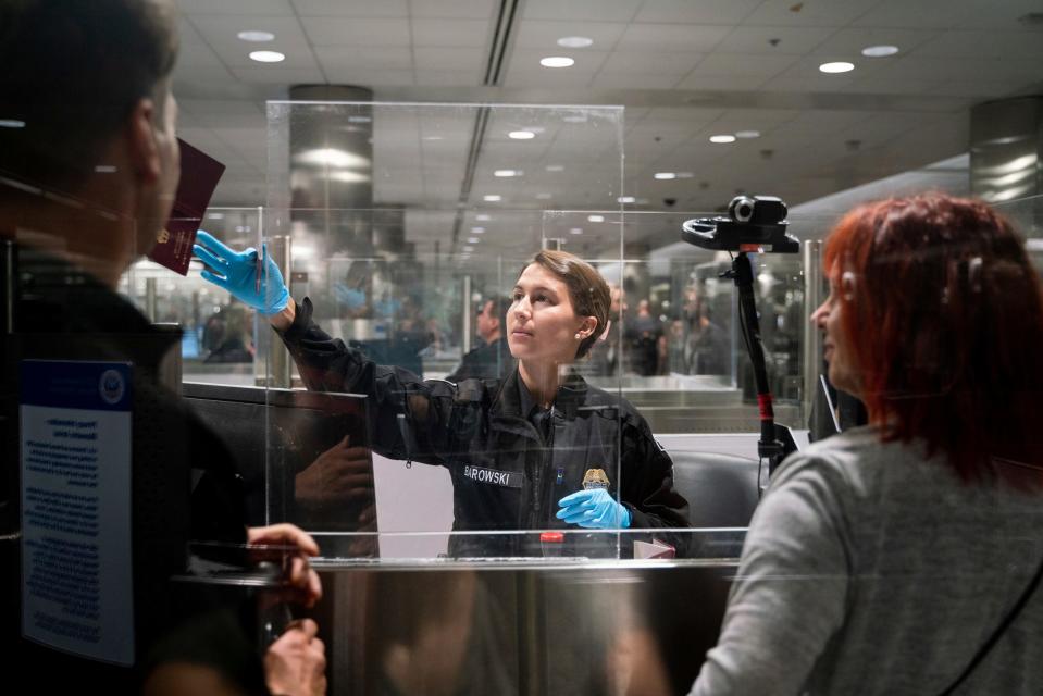 CBP officer G. Barowski, center, screens international travelers Henning Radtke, left, and Jeanette Radtke upon entering U.S. Customs and Border Protection at McNamara Terminal at Detroit Metro Airport in Romulus on July 28, 2023.