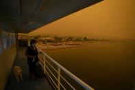 People use a ferry to evacuate from Pefki village on Evia island, about 189 kilometers (118 miles) north of Athens, Greece, Sunday, Aug. 8, 2021. Pillars of billowing smoke and ash are blocking out the sun above Greece's second-largest island as a days-old wildfire devours pristine forests and triggers more evacuation alerts. (AP Photo/Petros Karadjias)