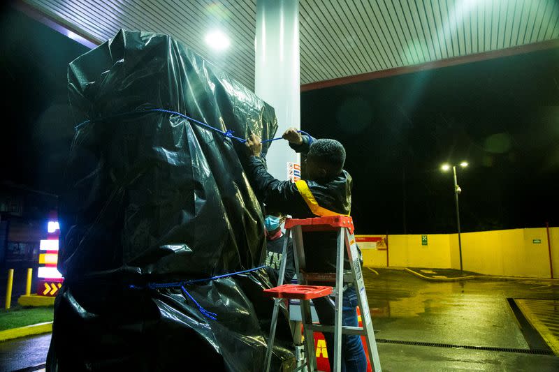 Un trabajador cubre un surtidor de gasolina con plástico después de que el huracán Julia golpeara las costas con viento y lluvia, en Bluefields,