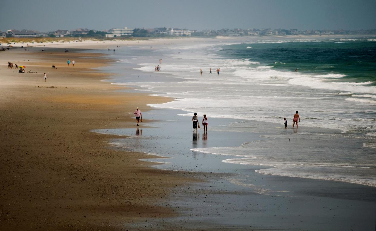 People walk along Wrightsville Beach.