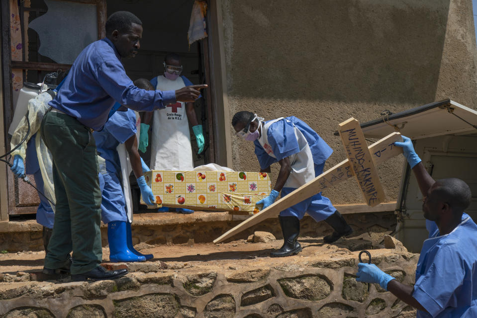 In this Sunday, July 14, 2019 photo, Red Cross workers carry the remains of 16-month-old Muhindo Kakinire from the morgue into a truck as health workers disinfect the area in Beni, Congo. The World Health Organization has declared the Ebola outbreak an international emergency. (AP Photo/Jerome Delay)