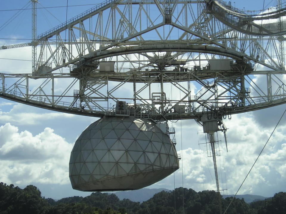 <p>Arecibo is the largest single aperture radio telescope in the world at about 1000 feet wide, located in the forests of Puerto Rico. The facility tunes in to pulsars, galaxies, and other cosmic phenomena, while occassionally hunting for aliens. Pictured here is the steering mechanism and antenna assembly at the top of the dish.</p>