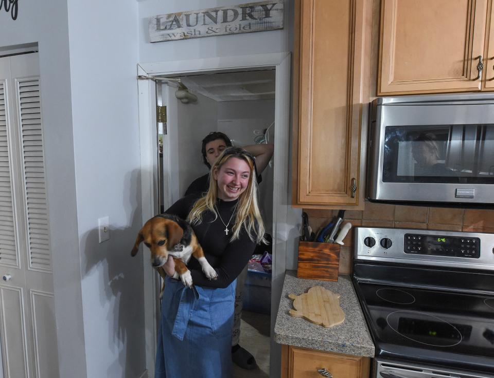 Carrying Cirby, the family beagle, Cassandra Murray, 21, (center) and her nephew, Michael DelVecchio, 16, exit Murray's bedroom, a garage-to-bedroom conversion she rents inside her sister Kristi Stewart's house in the Indian River Estates neighborhood in Fort Pierce. Murray, a pre-school teacher, rents the converted space in her sister's house while she is unable to find affordable housing so she can live on her own.