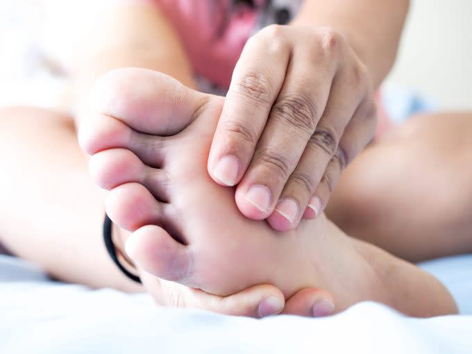 Asian woman sitting on bed Have foot pain Use hand massage to relieve pain And relax the foot muscles, Plantar Fasciitis disease.