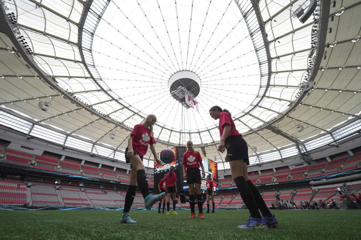 Youth soccer players kick a ball around on the field at B.C. Place stadium during a gathering to watch as Vancouver was chosen as one of the host cities for the 2026 FIFA World Cup soccer tournament, Thursday, June 16, 2022, at B.C. Place stadium in Vancouver, British Columbia. (Darryl Dyck/The Canadian Press via AP)
