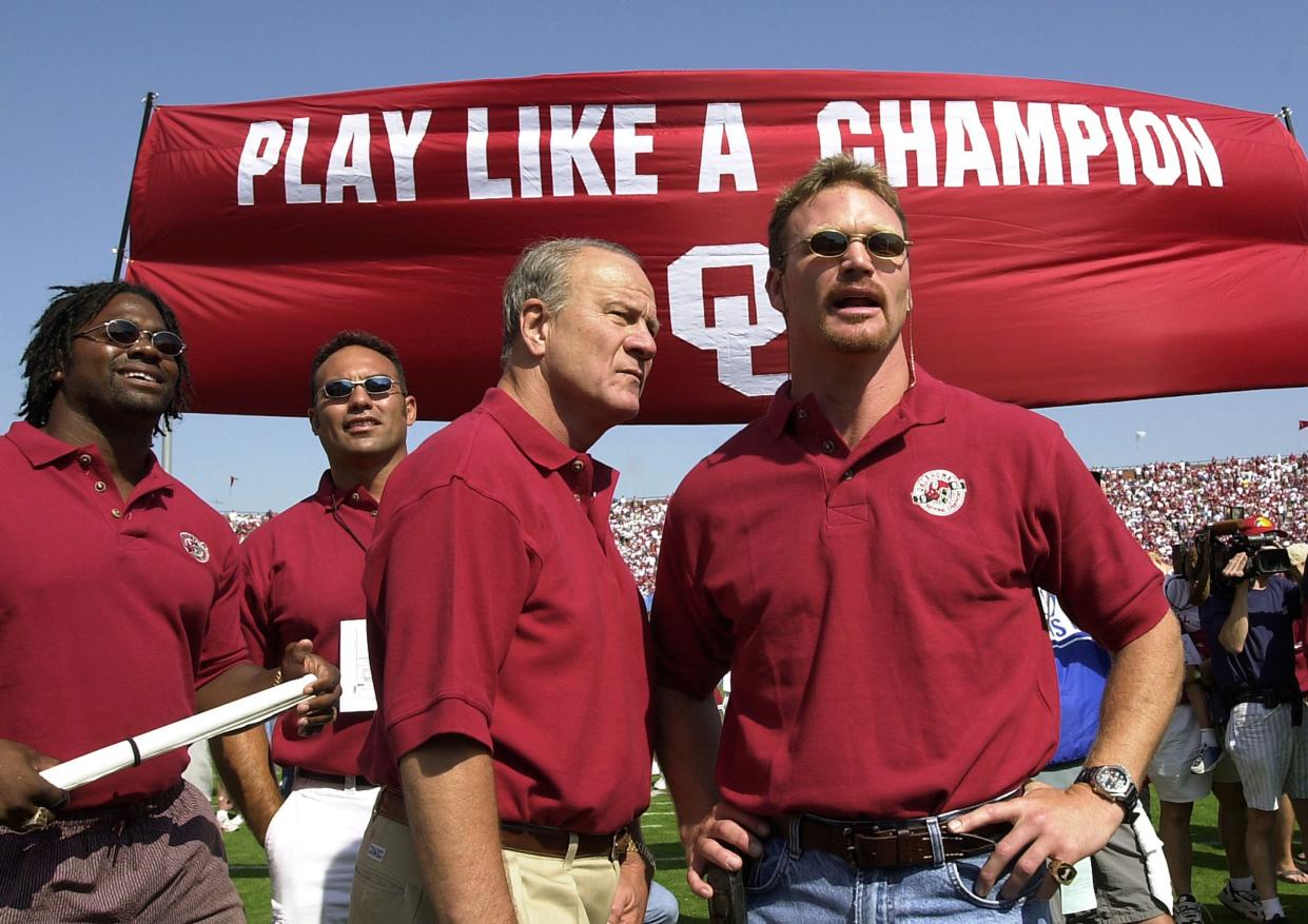 FOOTBALL: Coach Barry Switzer, center, is joined by Brian Bosworth, right, and other players from OU's 1985 national championship team on the field before Saturday's game against Rice. Behind Switzer is Tony Casillas. Other player ID is unknown. The players were introduced prior to the start of the game and they formed a "human tunnel" for this year's team to run through as they took the field.