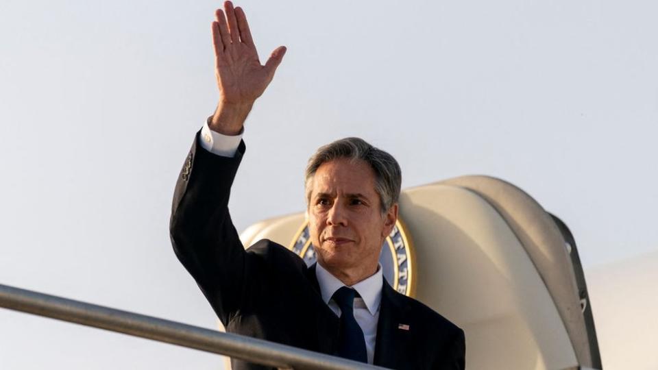 Antony Blinken waves as he exits his plane