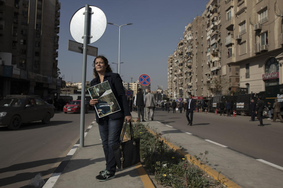 A woman holds a poster of ousted President Hosni Mubarak near the cemetery where he will be buried the Heliopolis neighborhood of Cairo, Egypt, Wednesday, Feb. 26, 2020. Egypt is holding a full-honors military funeral for Mubarak who was ousted from power in the 2011 Arab Spring uprising. Mubarak, 91, died Tuesday at a Cairo military hospital. (AP Photo/Nariman El-Mofty)