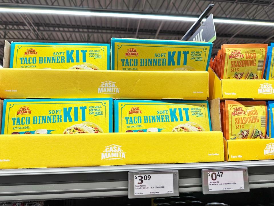 Bright-yellow boxes with teal lettering spelling ou "Soft taco dinner kit" on a shelf at Aldi