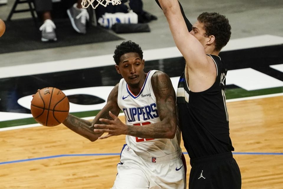 LA Clippers' Lou Williams looks to pass around Milwaukee Bucks' Brook Lopez during the first half of an NBA basketball game Sunday, Feb. 28, 2021, in Milwaukee. (AP Photo/Morry Gash)