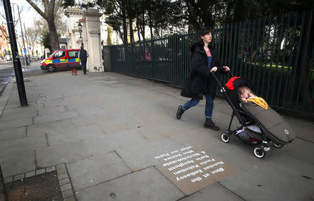 A woman wheels a pushchair past graffiti sprayed on the pavement near the entrance to the Russian embassy and ambassador's residence in London, Britain, March 15, 2018. REUTERS/Hannah McKay