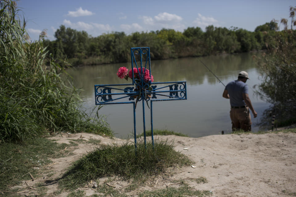 Un hombre pesca en la orilla mexicana del Río Grande (Bravo en México) junto a una cruz colocada en memoria de un migrante que murió cuando intentaba cruzar hacia Estados Unidos. (AP)