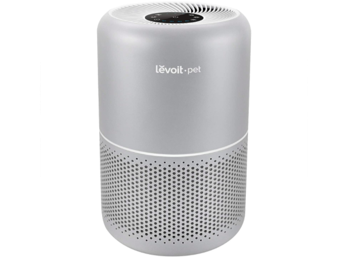 Silvery gray air purifying cylinder with perforated bottom and fan at the top. 