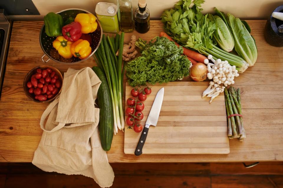 A butcher block countertop with fresh produce, a cutting board, and a kitchen knife on it