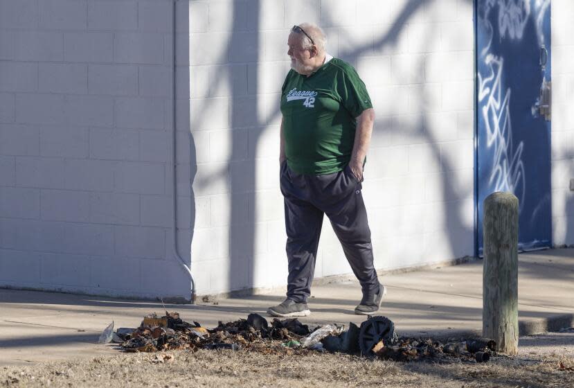 Bob Lutz walks past the charred remains of a dumpster