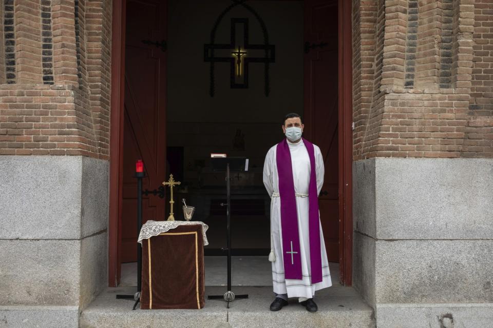 SPAIN: A priest wearing a face mask waits in front the cemetery chapel in Madrid.