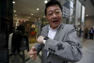 Customer Hajime Shimada, wearing his newly purchased Apple Watch, reacts as he tries to use it in front of Dover Street Market Ginza in Tokyo April 24, 2015. REUTERS/Issei Kato