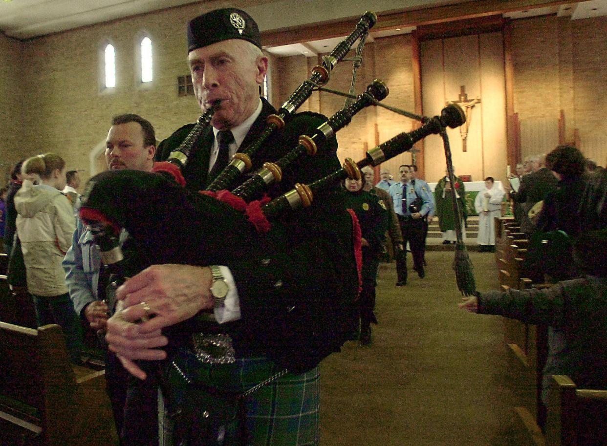 Bagpiper Terry Carroll leads the procession of area police fire and emergency workers out of The Church of the Ressurection after Sunday's Blue Mass in 2002.