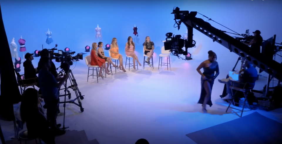 Former cast members sitting on a sound stage filming the Dance Moms reunion