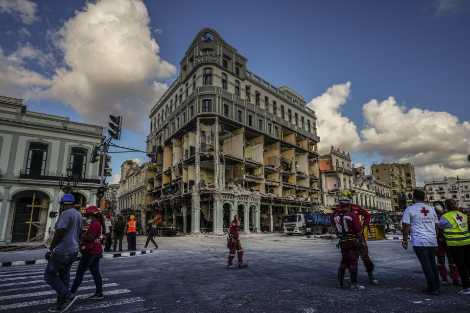 Rescue workers and members of the Cuban Red Cross walk in front of the damaged Hotel Saratoga, in Old Havana, Cuba, Wednesday, May 11, 2022. The May 6th explosion that devastated the hotel and killed dozens also badly damaged the Calvary Baptist Church, Cuba's most important Baptist church, which is pictured alongside the hotel, on the left. (AP Photo/Ramon Espinosa)