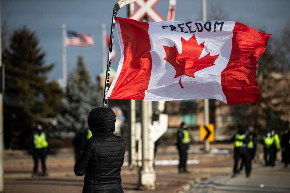 A protester carries a Canadian flag during an anti-mandate protest on Huron Church Road in Windsor, ON., on Feb. 12, 2022.