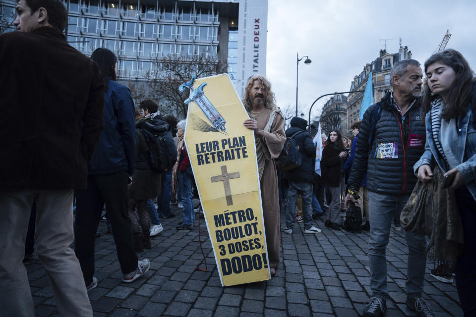 A protester holds a placard depicting a coffin that reads: ''Their pension plan: subway, work, three doses, sleep'' during a protest in Paris, Saturday, March 18, 2023. A spattering of protests were planned to continue in France over the weekend against President Macron's controversial pension reform, as garbage continued to reek in the streets of Paris and beyond owing to continuing action by refuse collectors. (AP Photo/Lewis Joly)