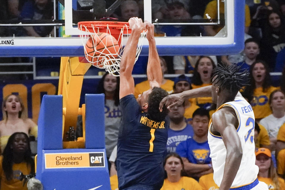 West Virginia's Emmitt Matthews Jr. (1) goes in for a dunk past Pittsburgh's Federiko Federiko during the first half of an NCAA college basketball game, Friday, Nov. 11, 2022, in Pittsburgh. (AP Photo/Keith Srakocic)