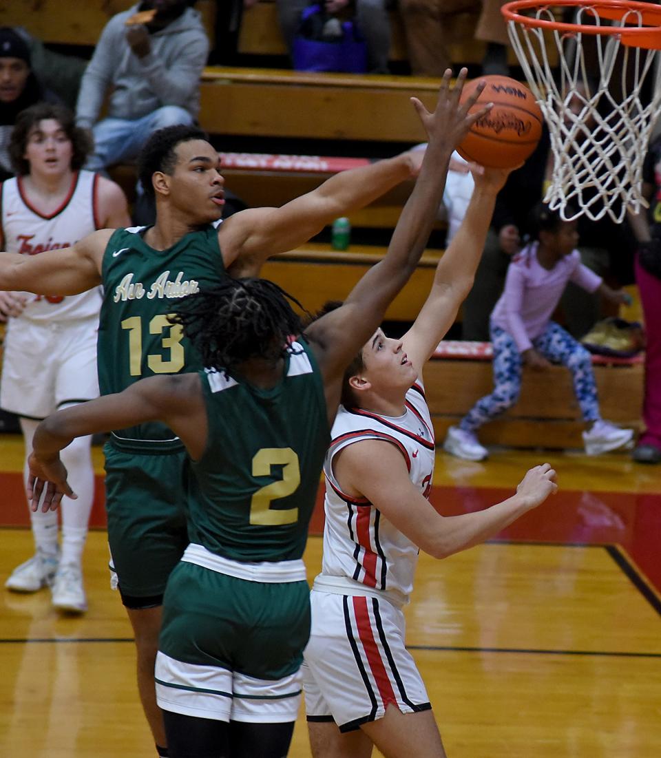 Lucis Rzepa of Monroe goes to the hoop but stopped by Mohamed Doumbouya and Braylon Dickerson of Ann Arbor Huron Tuesday. Monroe fell 58-27.