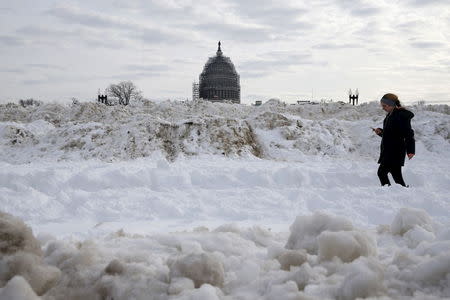 The U.S. Capitol dome can be seen behind piles of snow removed from parking areas and walkways around the Capitol grounds in Washington January 26, 2016. REUTERS/Jonathan Ernst