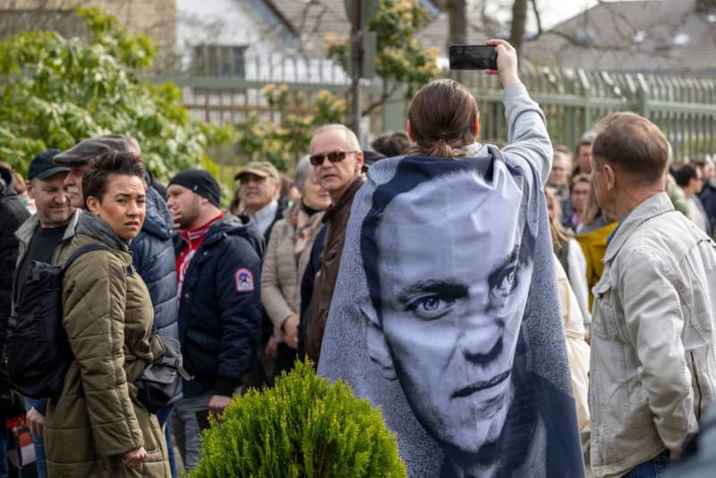 A demonstrator with a picture of the deceased opponent of the regime Alexei Navalny over his shoulders stands in front of the Russian Consulate General and protest against President Putin during the 2024 Russian presidential elections. Thomas Banneyer/dpa